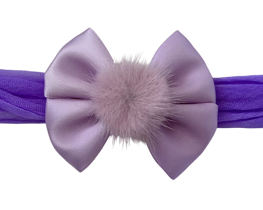Purple headband with a large bow and fluffy center on a white background