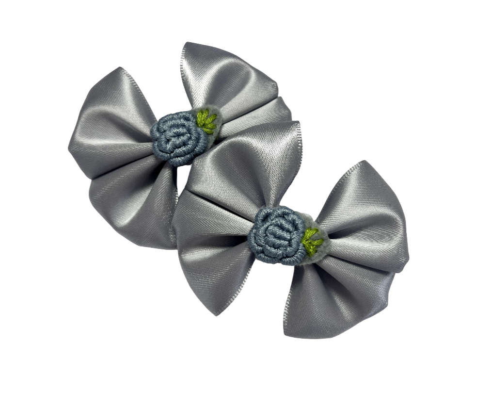 Two silver satin hair bows with floral centers on a white background