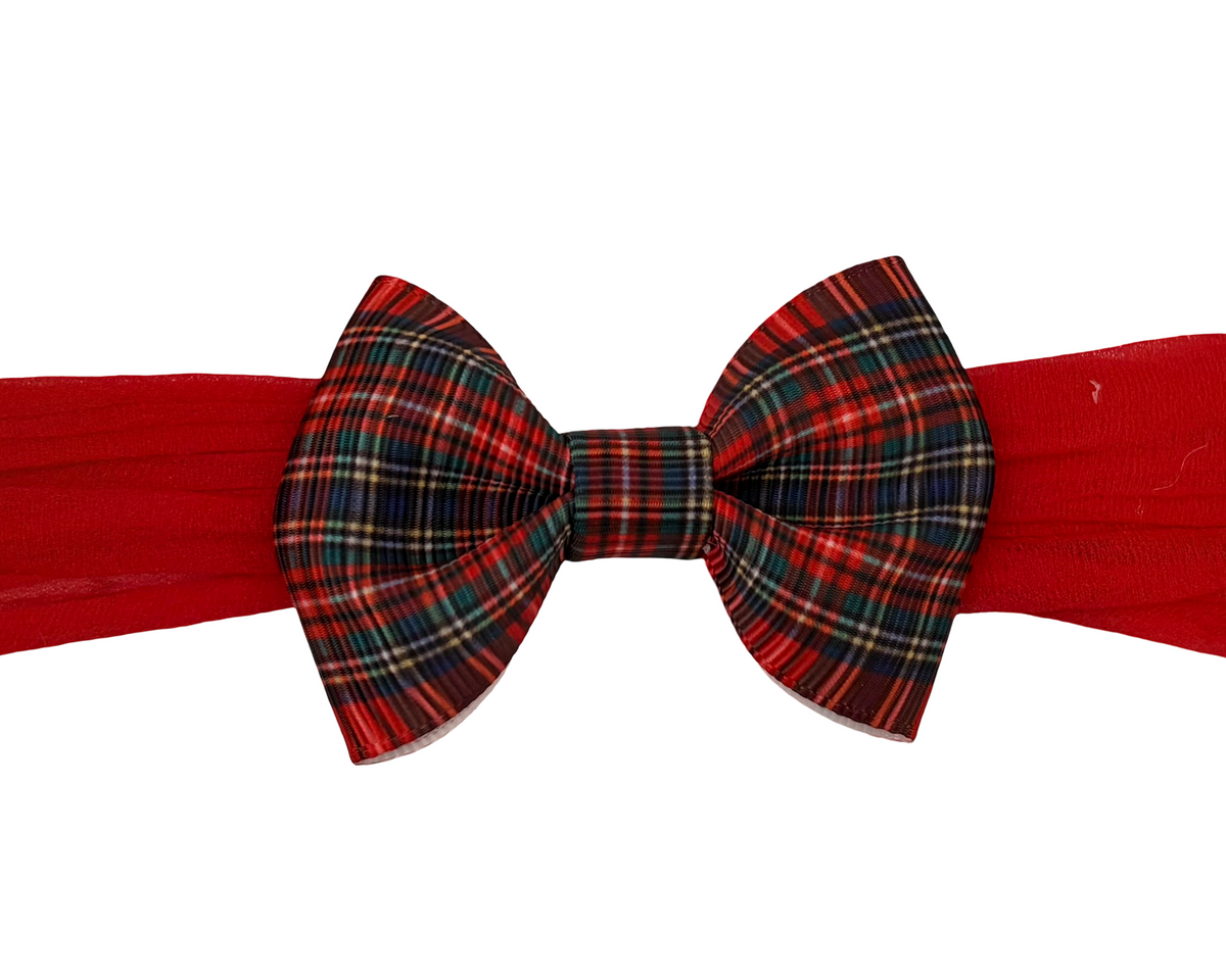 A red bow tie with a plaid pattern in red, green, and black, attached to a solid red neck strap, shown against a plain white background.