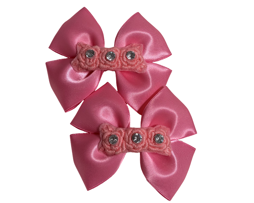 Two pink satin bows with decorative centers on a white background