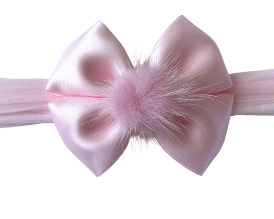 Pink headband with a large bow and fluffy center on a white background