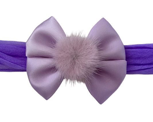 Purple headband with a large bow and fluffy center on a white background