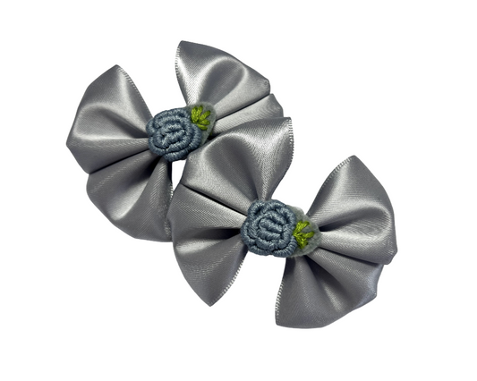 Two silver satin hair bows with floral centers on a white background