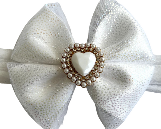 White bow headband with a heart-shaped pearl center on a white background