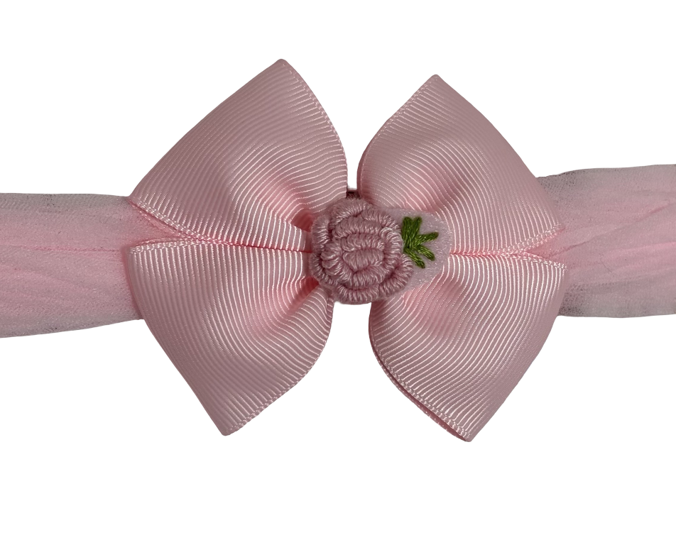Pink hair bow with a small flower on a white background