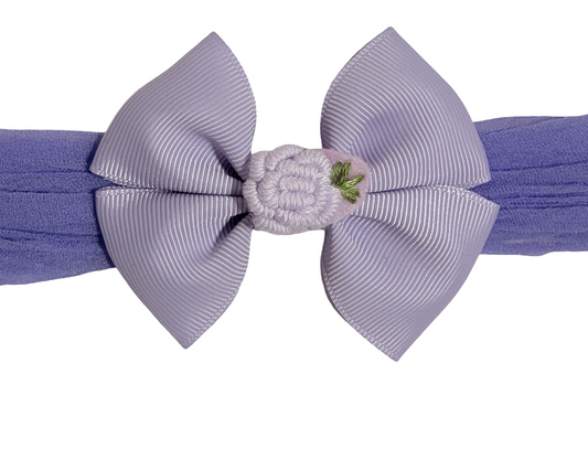 Purple headband with a large bow and small flower detail on a white background