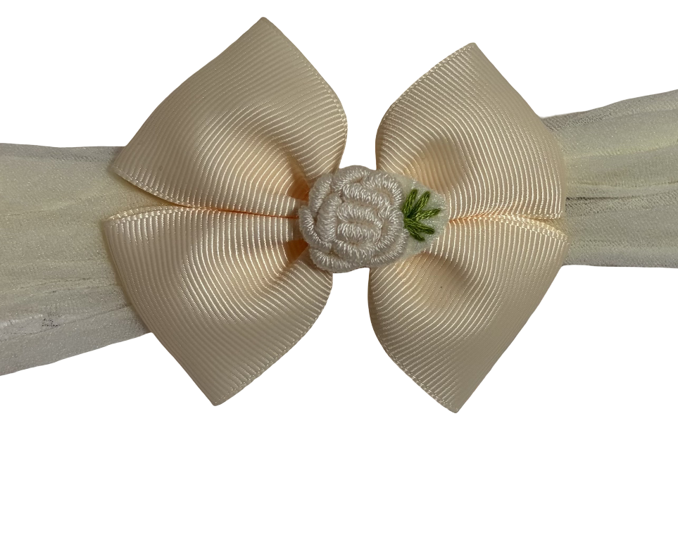 Beige headband with a large bow and small flower accessory on a white background