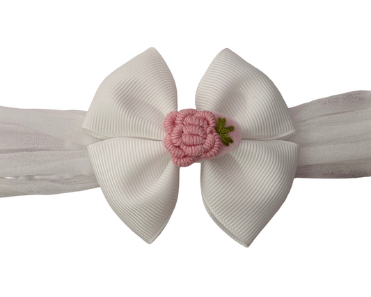 White headband with a large bow and pink flower on a white background