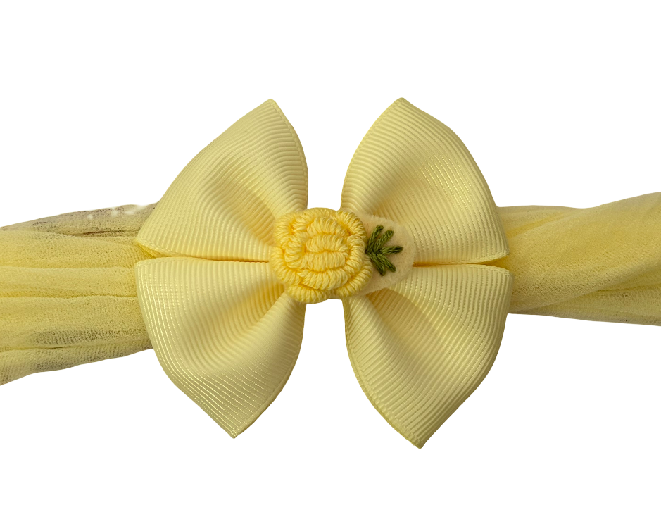 Yellow hair bow with a flower center on a white background