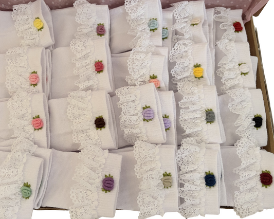 Set of white socks with embroidered designs on a cardboard box.
