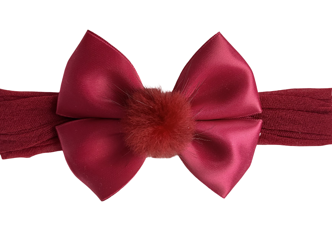 Red satin bow headband with a fluffy center on a white background