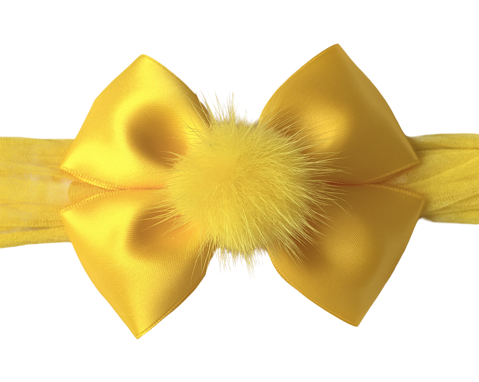 Yellow hair bow with fluffy center on a white background