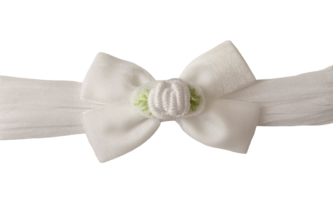 A white fabric headband featuring a large bow with a central white cord knot embellished with small green leaves, shown against a plain white background.