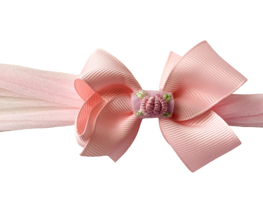 Pink hair bow with a small flower on a white background
