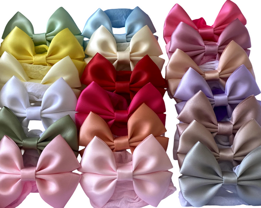 Collection of colorful satin hair bows arranged in a grid on a white background