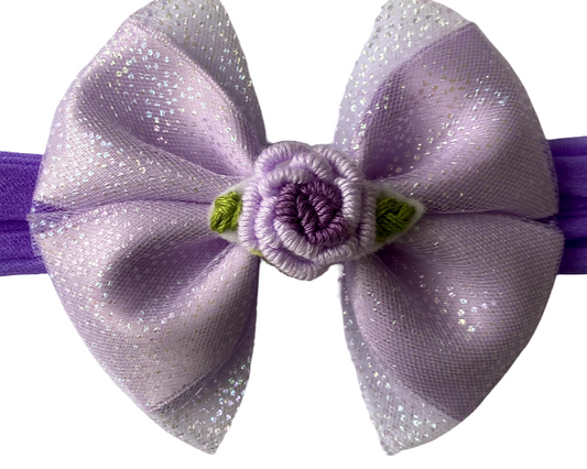 Purple headband with a large bow and floral detail on a white background
