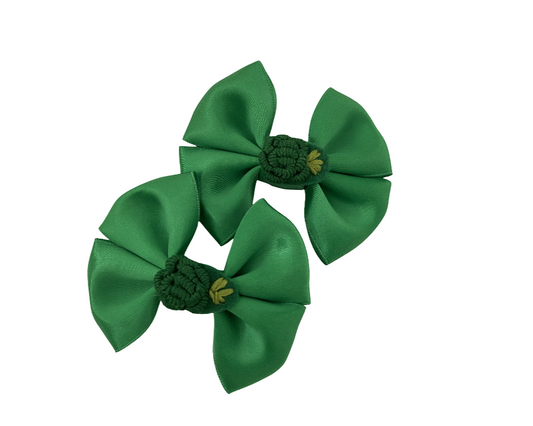 Two green hair bows with gold centers on a white background
